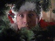 Chevy Chase as Clark Griswold peeking through the branches of a Christmas tree in National Lampoon's Christmas Vacation.