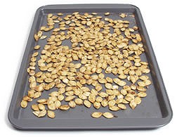 A cookie sheet filled with leftover pumpkin seeds.